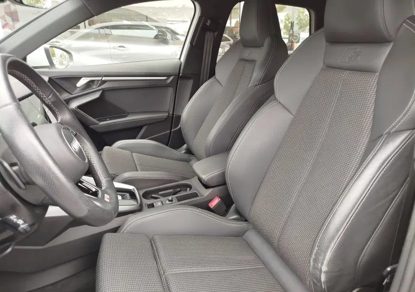 Vue intérieure côté conducteur de l'Audi A3 Sportback 30 TFSI S line 2022 avec sièges sport en cuir gris foncé.