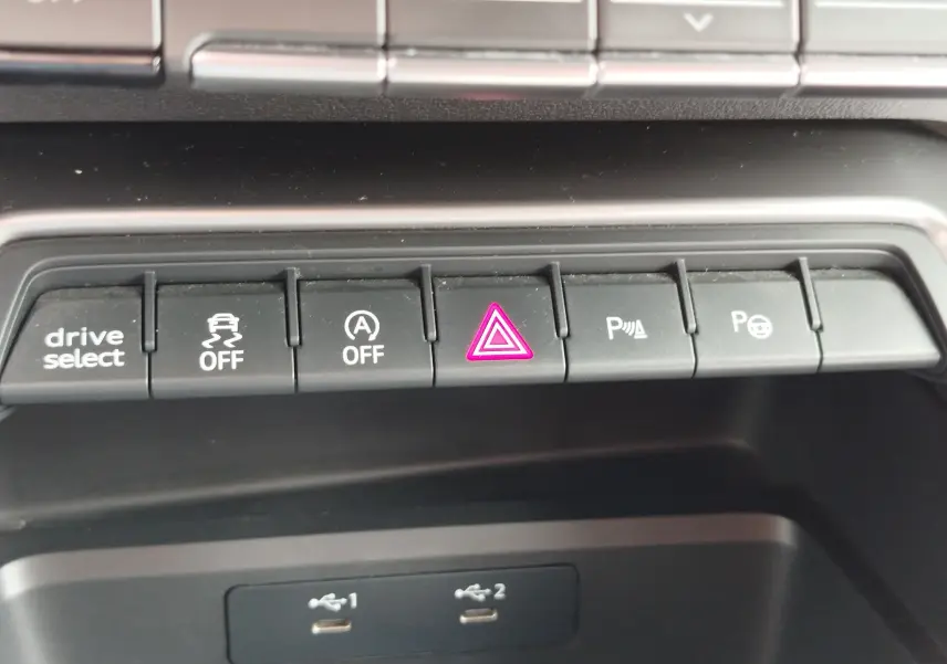 Gros plan sur la rangée de boutons de commande noirs avec témoin rouge d'alerte allumé dans l'Audi A3 Sportback blanc Glacier.
