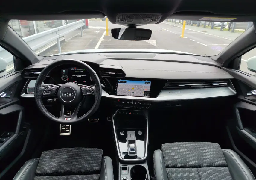 Vue intérieure avant de l'Audi A3 Sportback 2022, tableau de bord moderne avec écran tactile et volant multifonction noir.