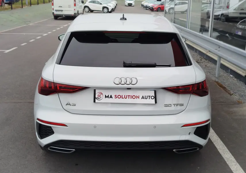 Vue arrière d'une Audi A3 Sportback blanc glacier métallisé, avec feux LED et double sortie d'échappement intégrée.