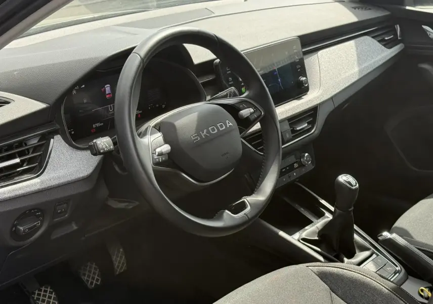 Vue intérieure côté conducteur du Skoda Scala TSI 116 gris graphite, volant cuir multifonctions et levier de vitesses manuel.