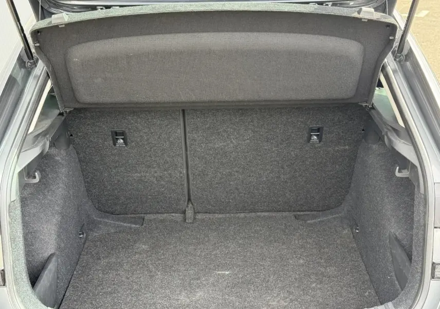 Vue intérieure du coffre ouvert d'une Skoda Scala TSI 116 gris graphite, montrant l'espace de rangement vide et tapissé.