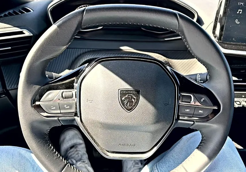 Vue intérieure centrée sur le volant cuir noir du Peugeot 2008 1.2 100 style avec commandes multifonctions visibles.