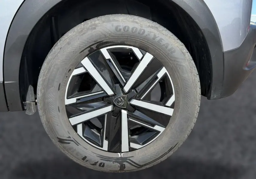 Gros plan sur la roue avant gauche du Peugeot 2008 gris, avec jante alliage noire et argentée au design moderne.