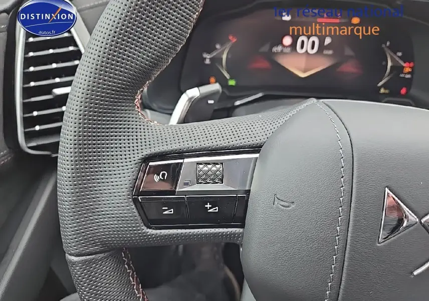 Gros plan sur le volant cuir perforé du DS7 1.5 BlueHDi 130 Pallas avec commandes intégrées et tableau de bord numérique visible.