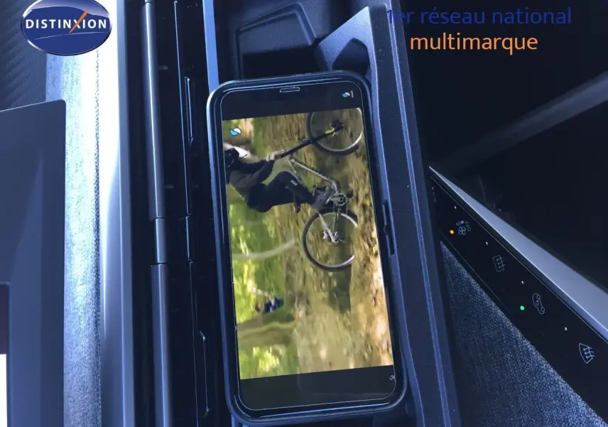 Intérieur du Peugeot 5008 Hybrid 2025 montrant le support smartphone et la console centrale noire avec commandes tactiles.