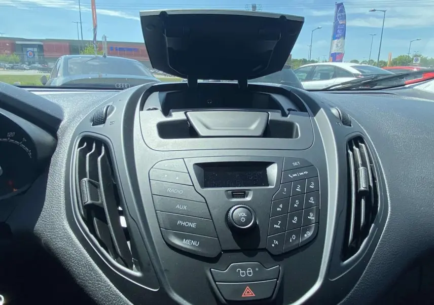 Vue rapprochée du tableau de bord noir du Ford Tourneo Courier 2022, mettant en valeur la console centrale avec commandes radio et ventilation.