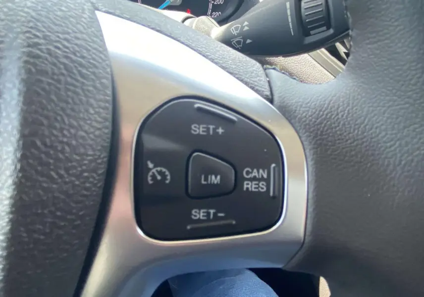 Gros plan sur les commandes du régulateur de vitesse au volant cuir du Ford Tourneo Courier blanc 2022.