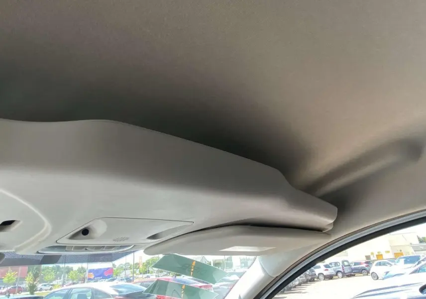 Vue intérieure du plafond et pare-soleil côté conducteur d'un Ford Tourneo Courier blanc 2022, avec parking en arrière-plan.