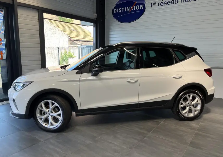 SEAT ARONA blanc Nevada vue de profil côté gauche en intérieur avec toit noir et jantes alliage 16 pouces.