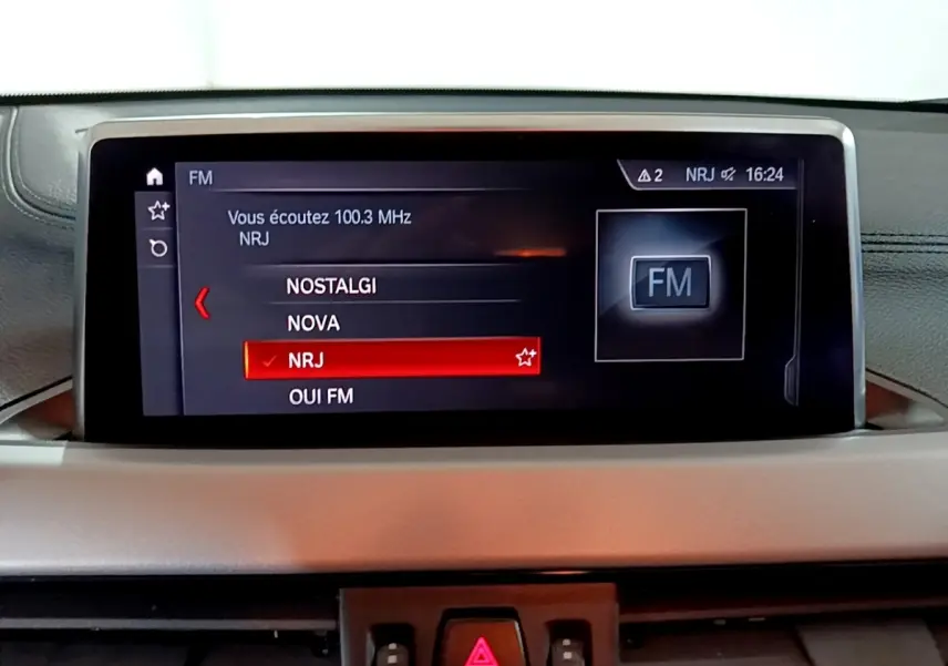 Écran central du tableau de bord du BMW X2 sDrive18i 2023 affichant la sélection radio FM NRJ.