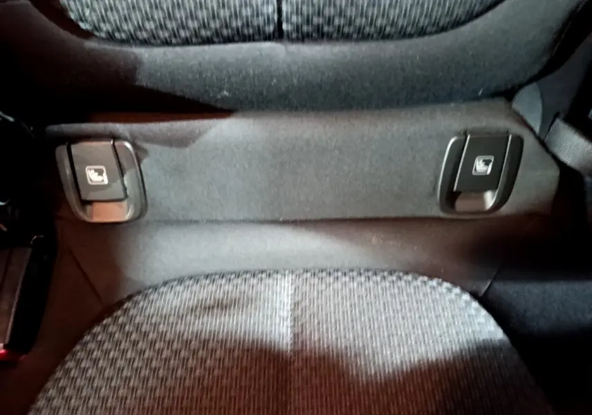 Détail des commandes de rabattement des sièges arrière sur banquette tissu gris du BMW X2 noir 2023.