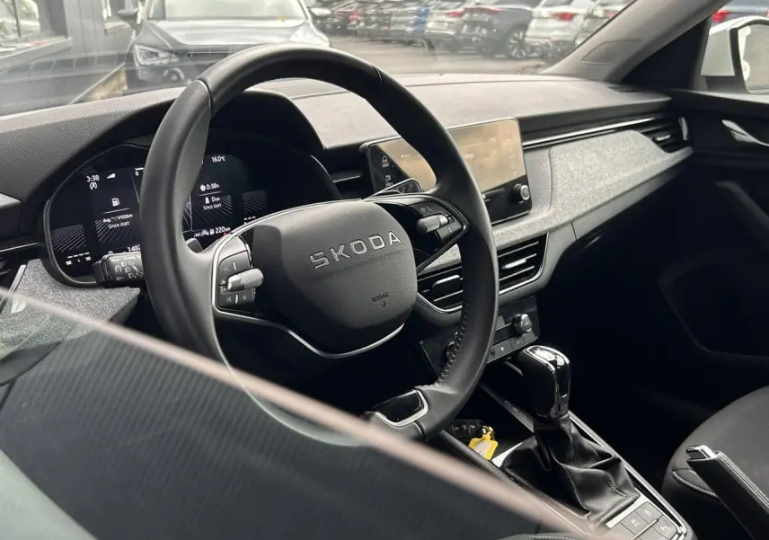Vue intérieure côté conducteur du Skoda Scala 2025, volant multifonctions noir et écran tactile central visible.