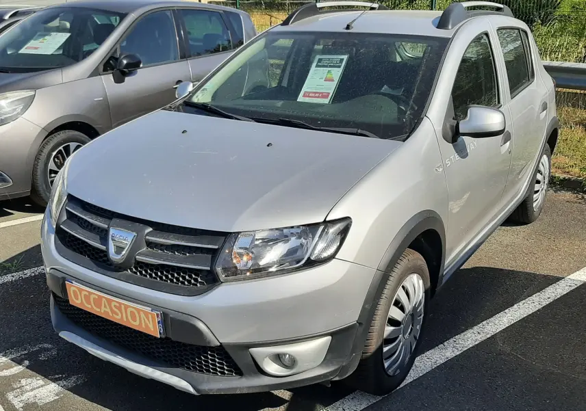 Dacia Sandero Stepway gris platine vue 3/4 avant droit, avec badge Stepway sur la porte et plaque "OCCASION".