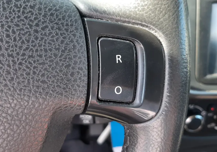 Gros plan sur les boutons R et O du volant en cuir noir d'une Dacia Sandero Stepway gris platine, intérieur visible en arrière-plan.