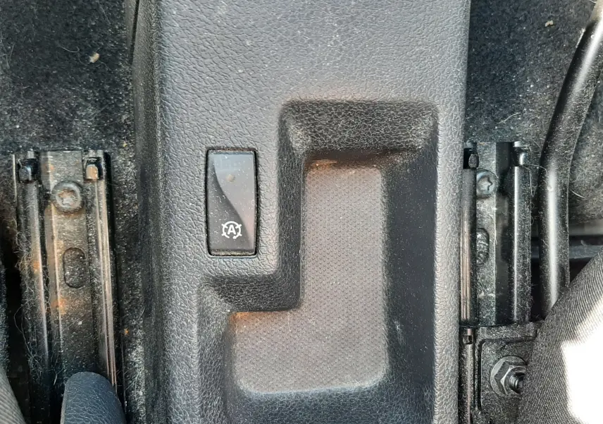 Gros plan sur le levier de frein à main et bouton de désactivation du système start-stop dans une Dacia Sandero Stepway gris platine.