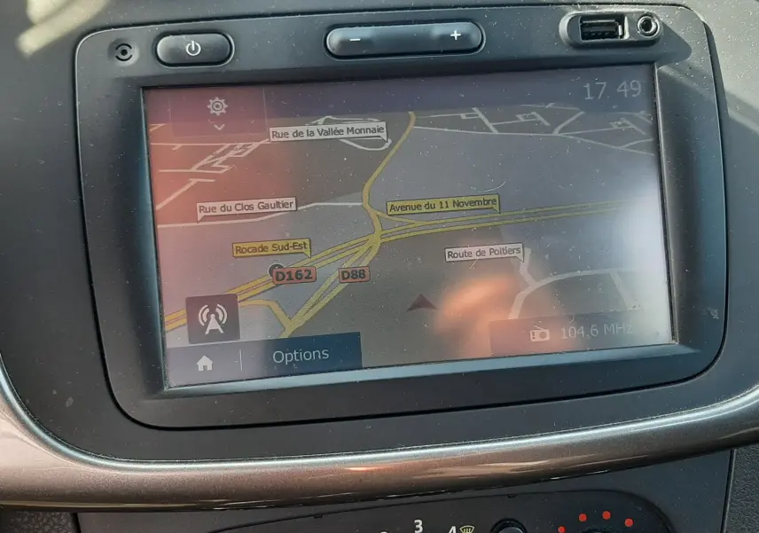 Écran tactile du GPS et commandes de climatisation dans le tableau de bord d'une Dacia Sandero Stepway gris platine.