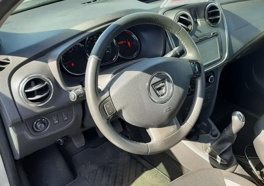 Vue intérieure côté conducteur de la Dacia Sandero Stepway 2016, volant multifonction et tableau de bord gris noir.