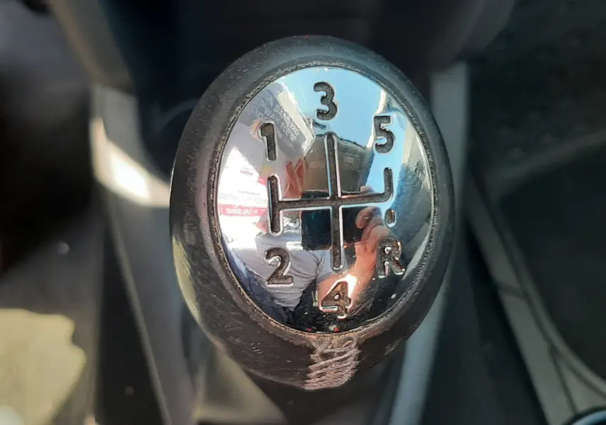 Gros plan sur le levier de vitesse manuel chromé de la Dacia Sandero Stepway gris platine, intérieur tissu gris-noir.