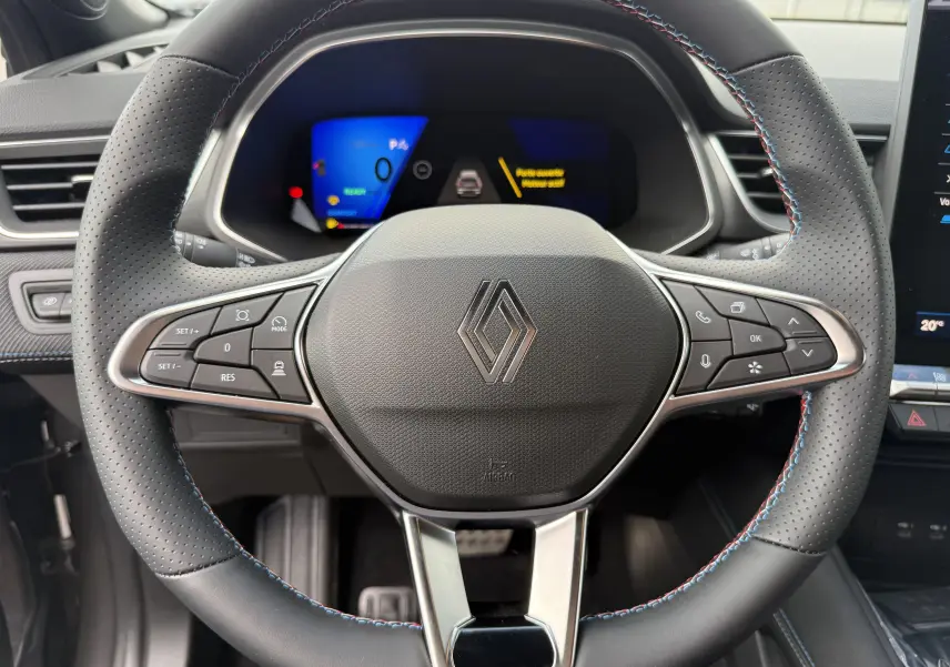 Vue rapprochée du volant perforé noir avec surpiqûres tricolores du Renault Symbioz Esprit Alpine 2026, tableau de bord digital visible.