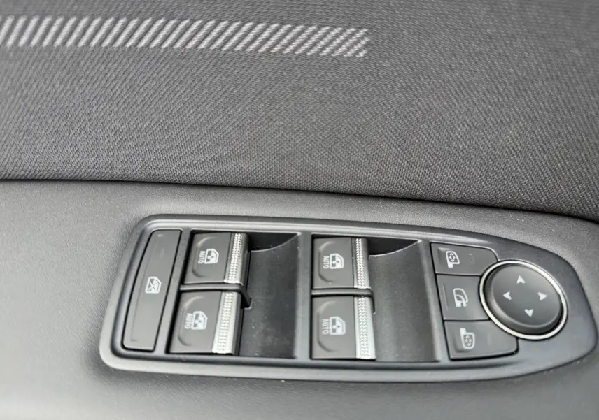 Gros plan sur les commandes des vitres électriques et rétroviseurs côté gauche d'une Renault Symbioz gris cassiopée métal.