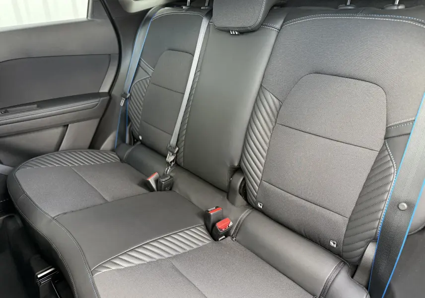 Vue intérieure arrière des sièges noirs et gris du Renault Symbioz Esprit Alpine, avec surpiqûres bleues et ceintures visibles.