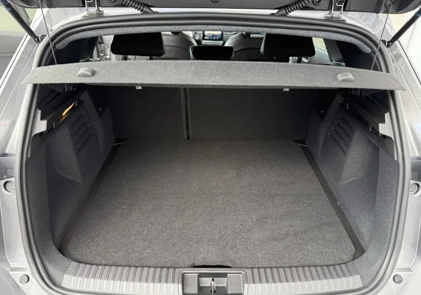Coffre ouvert vu de l'arrière d'une Renault Symbioz gris cassiopée métal, montrant un espace de chargement vide et propre.