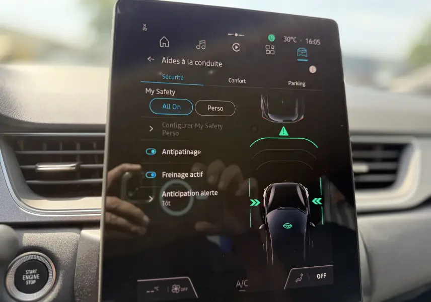 Écran tactile central du Renault Captur 2025 affichant les aides à la conduite, avec tableau de bord gris en arrière-plan.