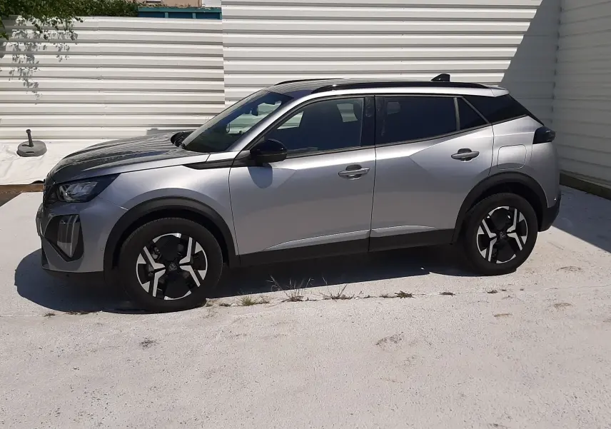 Peugeot 2008 gris Artense vue de profil côté gauche, barres de toit noires et jantes distinctives.