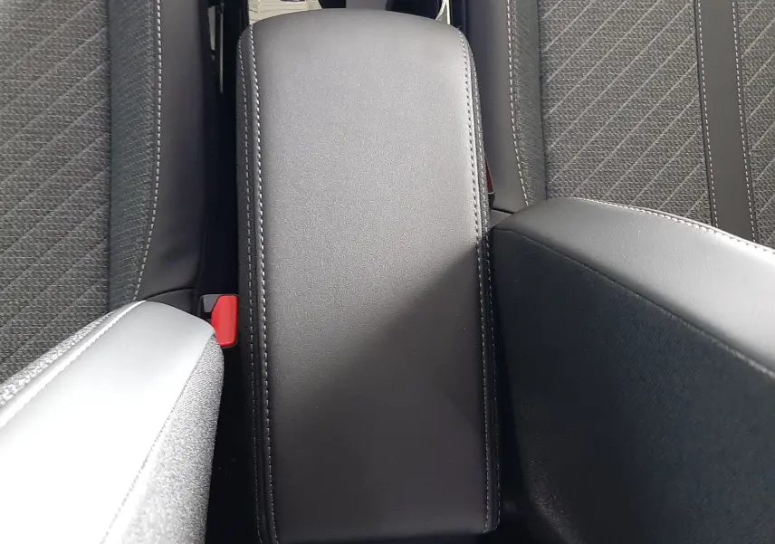 Vue plongeante sur l'accoudoir central noir et les sièges tissu noir du Peugeot 2008 1.2 Hybrid 145ch Allure 2025.