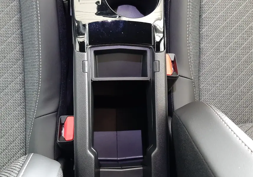 Vue plongeante sur la console centrale noire du Peugeot 2008 1.2 Hybrid 145ch Allure avec porte-gobelets et sièges tissu gris.