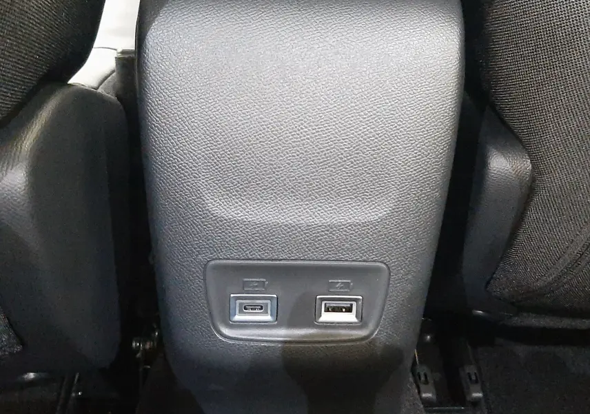 Vue rapprochée de la console arrière noire du Peugeot 2008 1.2 Hybrid 145ch Allure avec ports USB visibles.