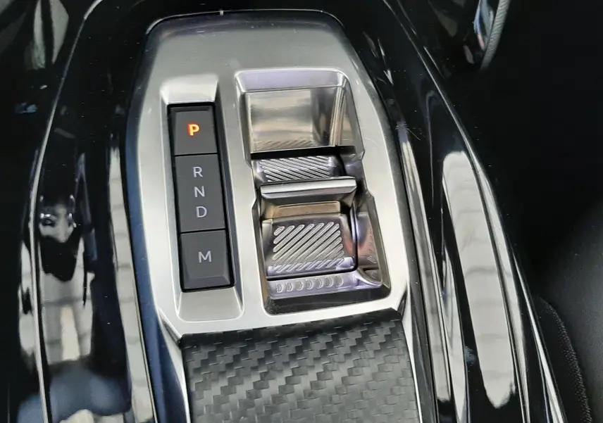 Gros plan sur la console centrale noire avec sélecteur de boîte automatique et finition carbone du Peugeot 2008 gris Artense.