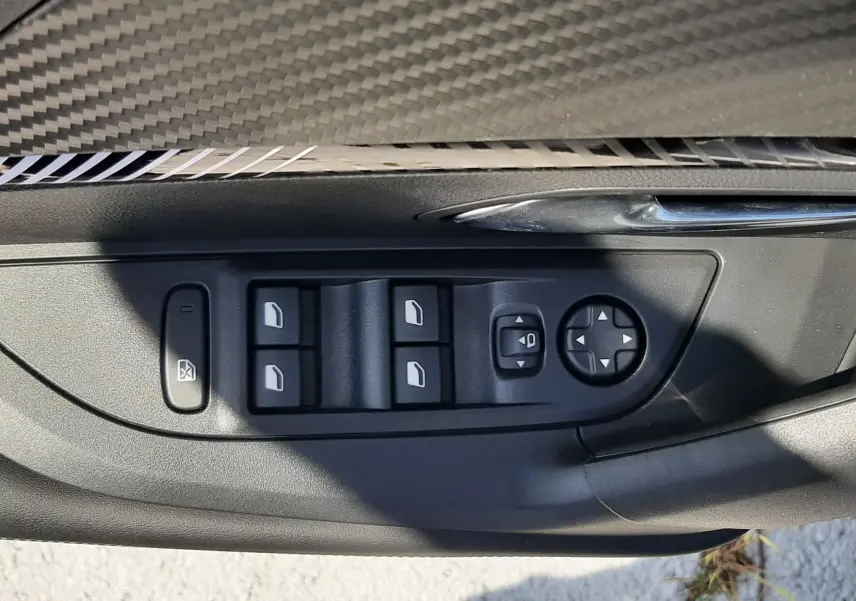 Détail des commandes des vitres et rétroviseurs côté conducteur du Peugeot 2008 gris Artense, intérieur noir.