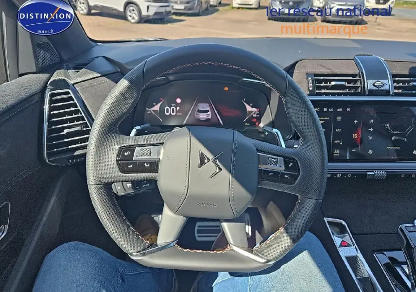 Vue intérieure centrée sur le volant cuir DS d'un DS7 2025 avec tableau de bord numérique et écran tactile.