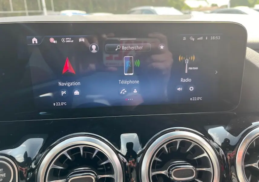 Écran tactile central du Mercedes GLA 250 e hybride 2024 affichant navigation, téléphone et radio, avec aérateurs ronds chromés.