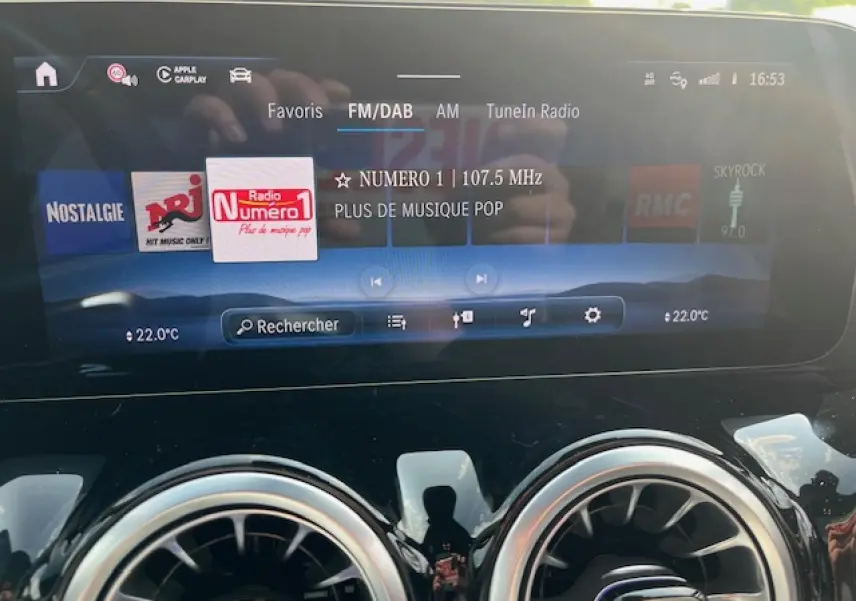 Écran tactile central du Mercedes GLA 250 e blanc 2024 affichant la radio FM/DAB et la température à 22°C