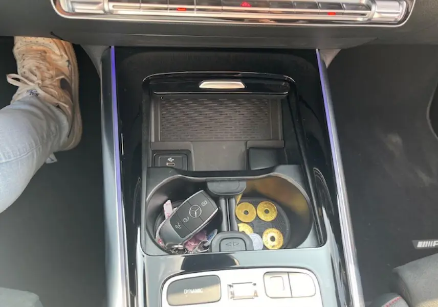 Vue plongeante sur la console centrale noire brillante du Mercedes GLA 250 e hybride avec clé et pièces dans les porte-gobelets.