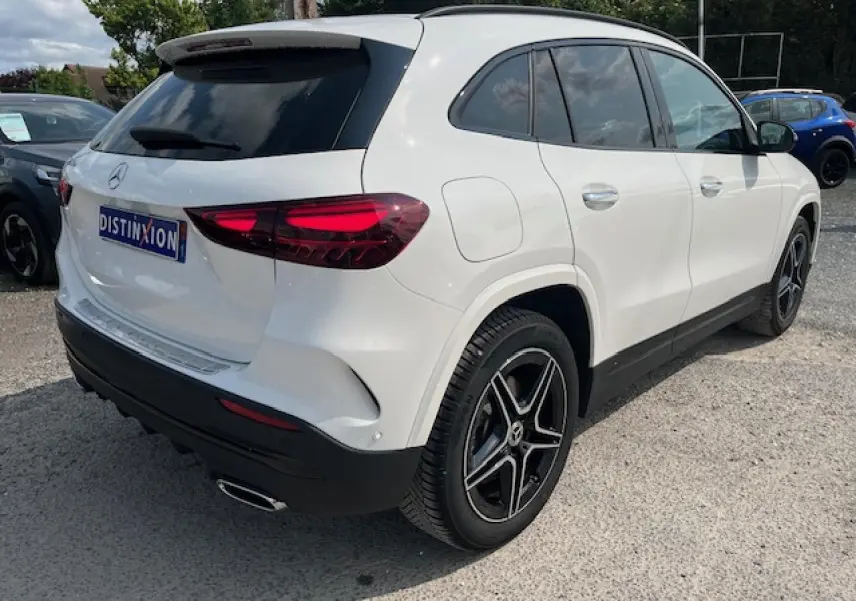 Vue 3/4 arrière droite d'un Mercedes GLA 250 e blanc avec jantes AMG noires et feux arrière LED distinctifs.