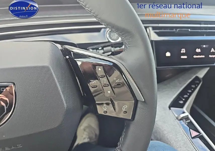 Gros plan sur les commandes au volant cuir noir du Peugeot 3008 2025 hybride, avec écran tactile en arrière-plan.