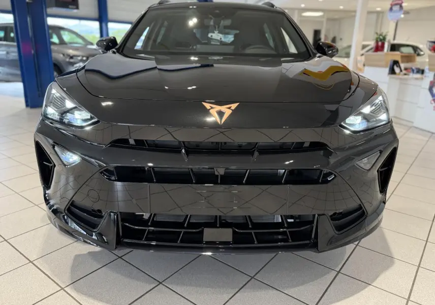 Vue avant rapprochée du CUPRA Formentor noir Night avec logo cuivré et phares Full LED allumés en showroom.