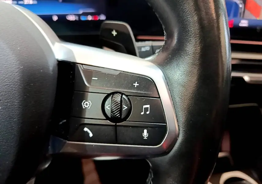 Gros plan sur les commandes multifonctions en cuir noir du volant du BMW X1 xDrive23i M Sport 2023.