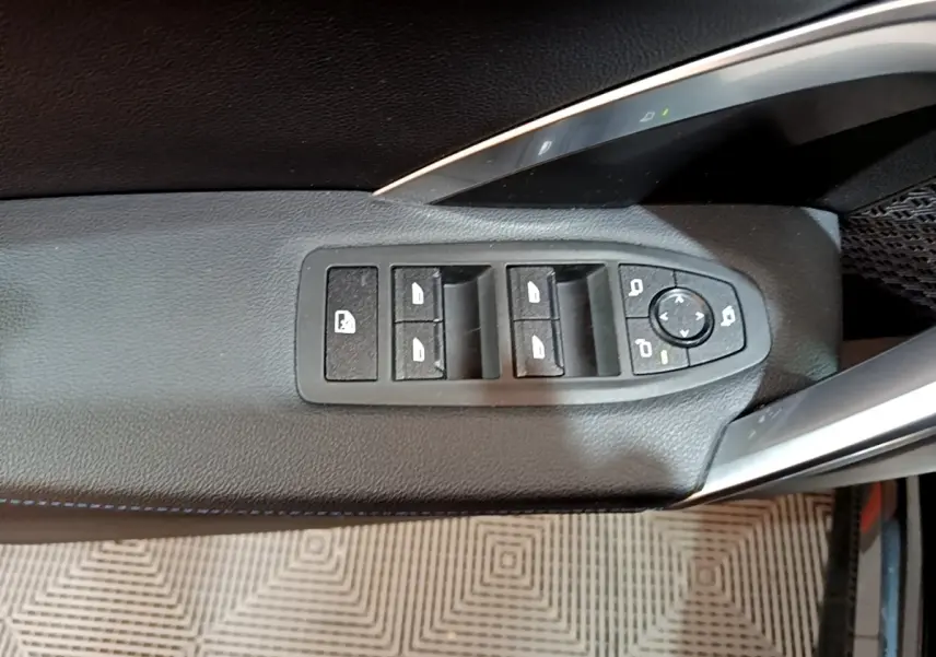 Gros plan sur les commandes de lève-vitres et rétroviseurs côté gauche noir du BMW X1 xDrive23i M Sport 2023.