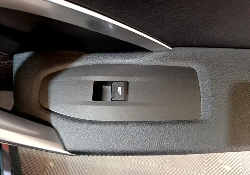 Gros plan sur le bouton de commande de la vitre électrique côté conducteur d'un BMW X1 noir, intérieur cuir noir.