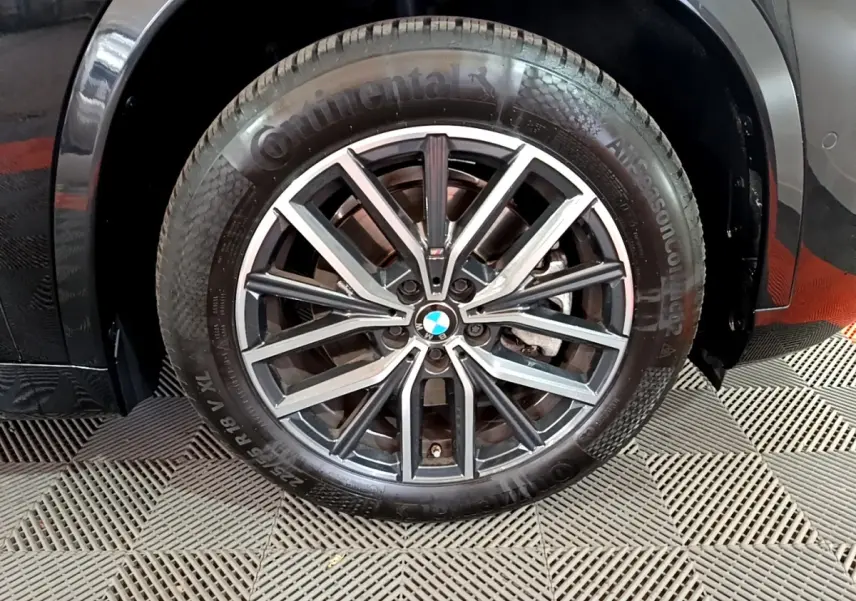 Gros plan sur la roue avant droite noire d’un BMW X1 xDrive23i M Sport 2023 avec jante alliage multibranches.