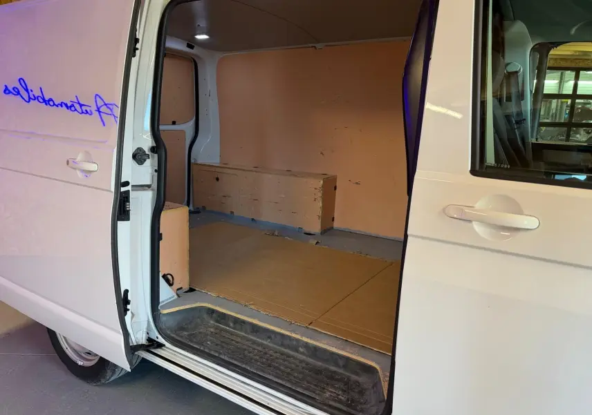 Vue latérale gauche du Volkswagen Transporter blanc 2019 avec porte coulissante ouverte montrant l'espace de chargement vide.
