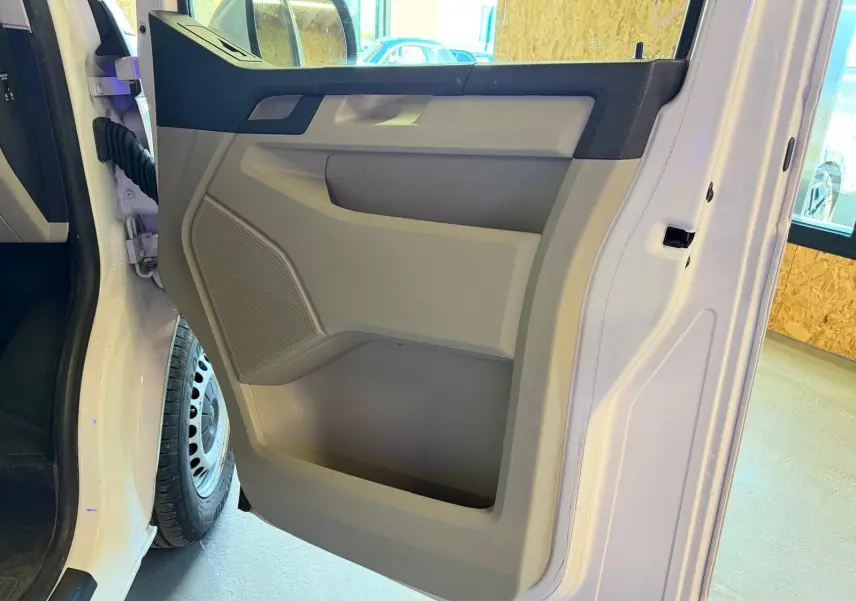 Vue rapprochée de la porte avant gauche blanche du Volkswagen Transporter 2019, avec panneau intérieur beige et noir.