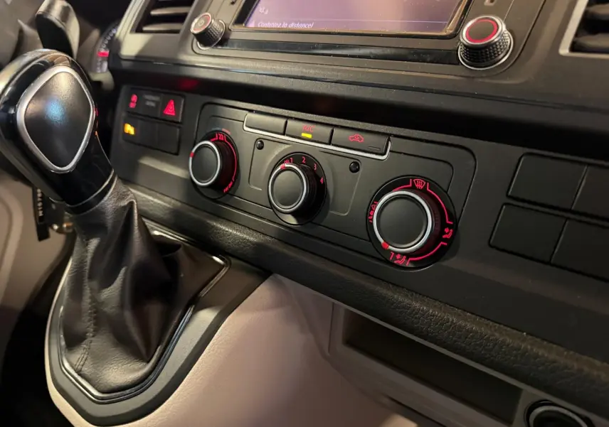Vue rapprochée de la console centrale noire du Volkswagen Transporter 2019 avec levier de vitesse et commandes de climatisation.