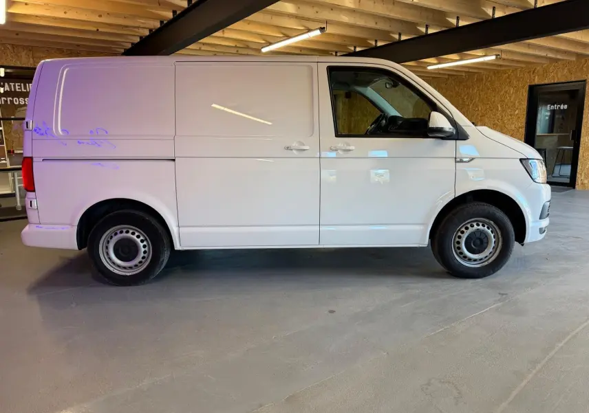 Vue de profil côté gauche d’un utilitaire Volkswagen Transporter blanc, version Business Life Plus, dans un garage intérieur.