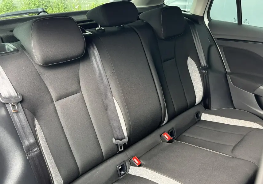 Vue intérieure de la banquette arrière du Skoda Scala 2025, sièges noirs avec surpiqûres grises et ceintures visibles.